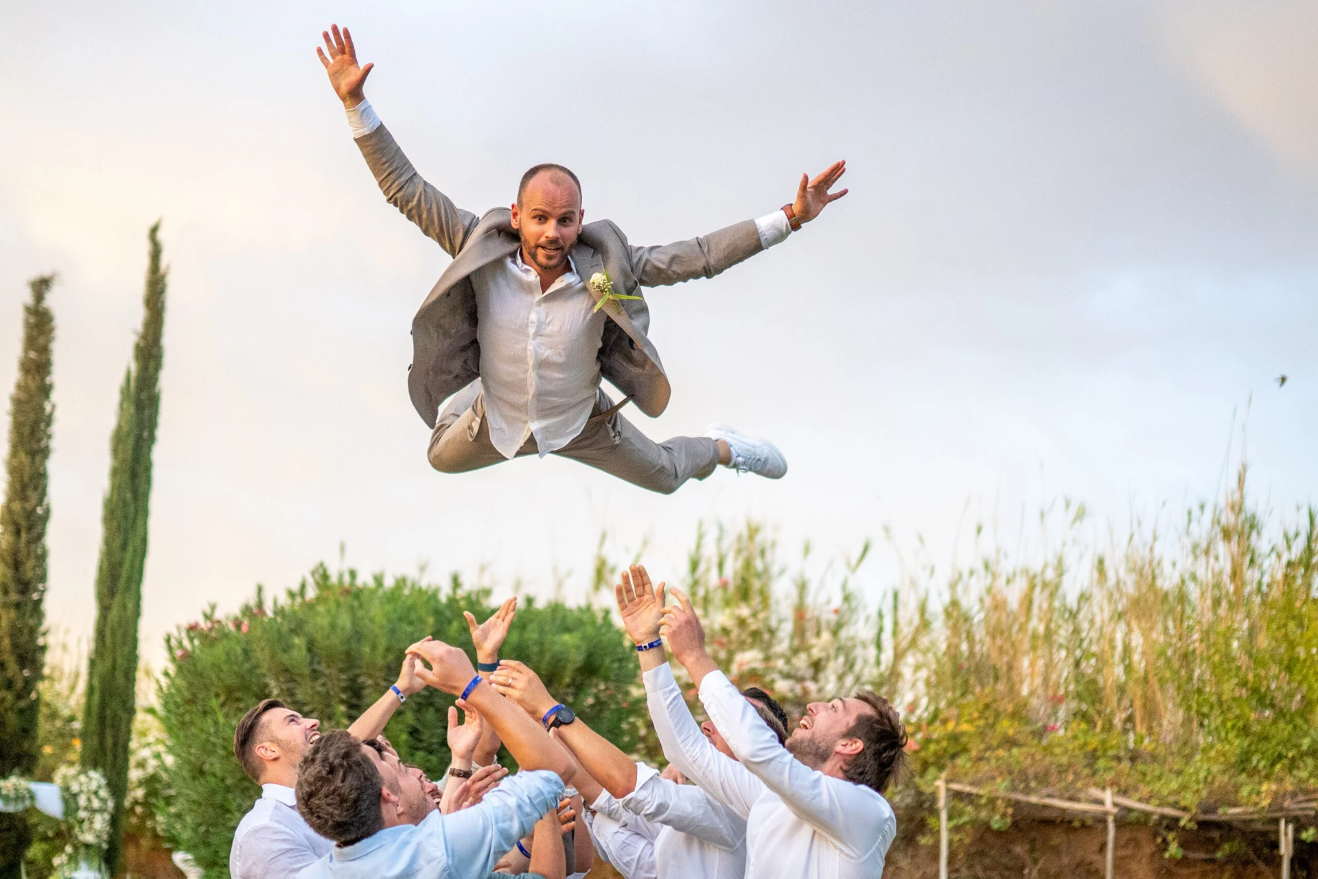 A groom tossed into the air by cheering wedding guests