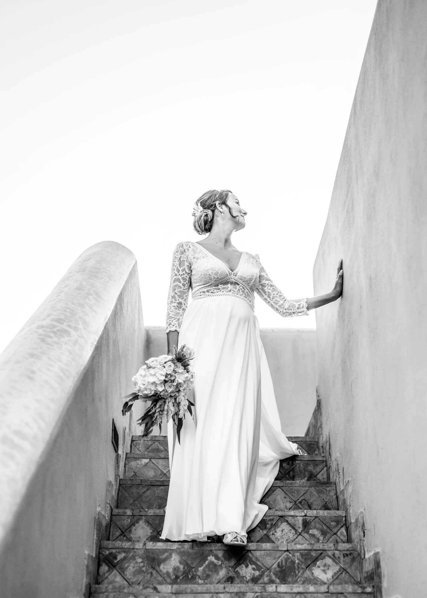 Bride on warm pink architectural stairs — original black-and-white edit