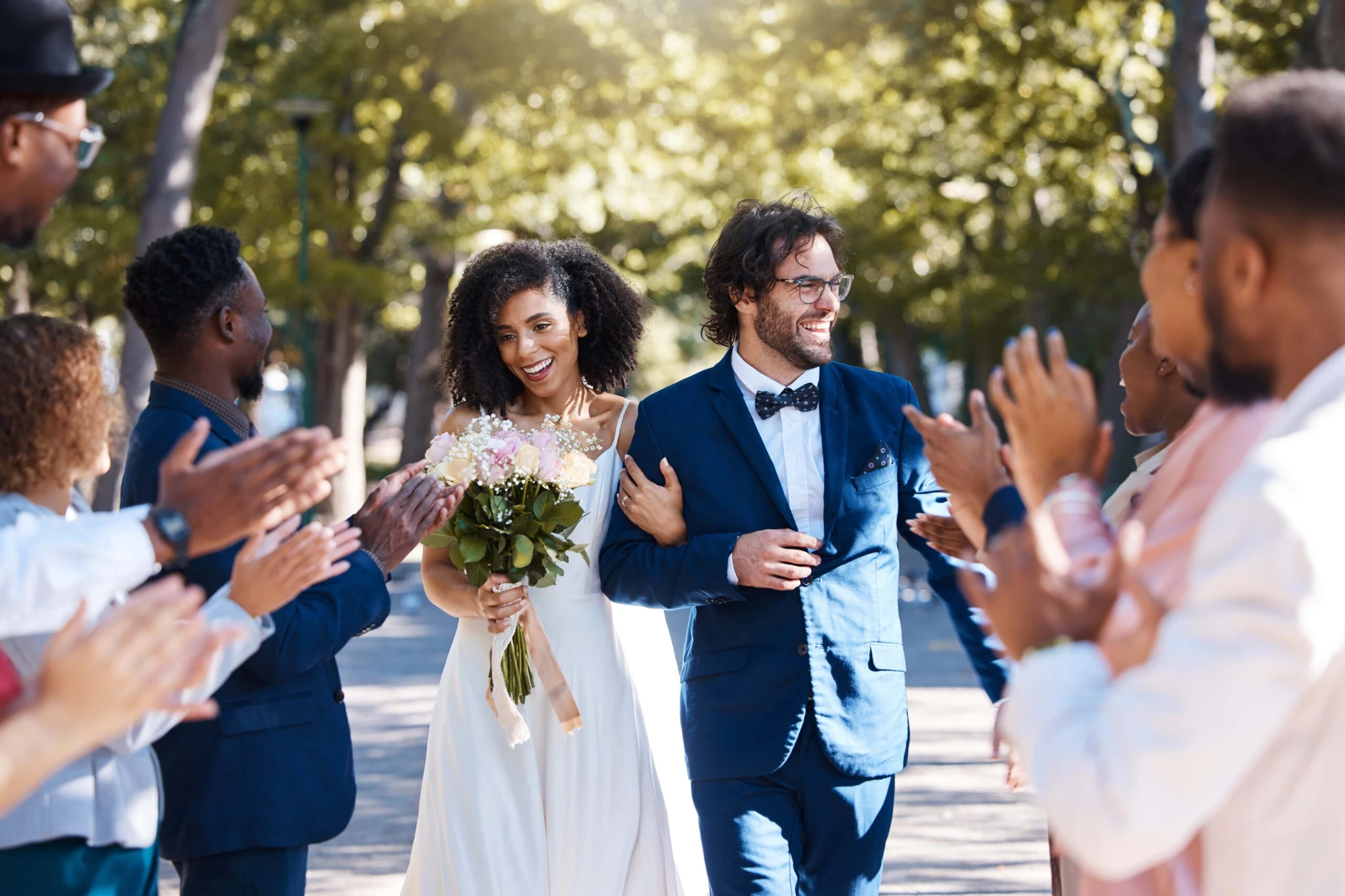 Newlyweds walking between applauding wedding guests
